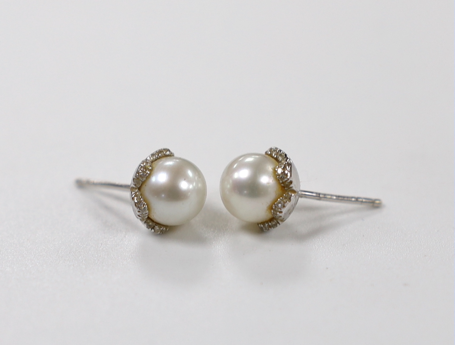 A pair of 18ct white gold, cultured pearl and diamond chip set ear studs, pearl diameter 8.15mm, gross weight 4.1 grams.